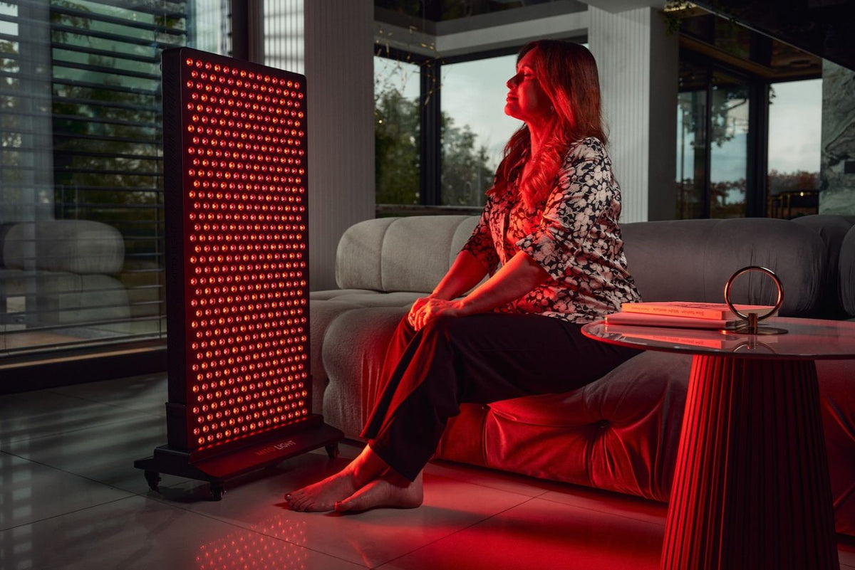 Vrouw zit in de woonkamer op een bank voor een MitoLight Mitohacker rood lichttherapie paneel